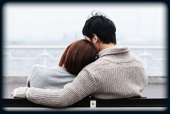 海が見えるベンチで肩を寄せ合うカップル